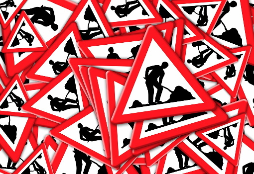 Kilka nałożonych na siebie znaków drogowych ostrzegających przed pracami drogowymi.