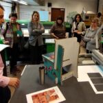 W pracowni Kulkokracja pracownik objaśnia działanie poszczególnych maszyn. Uczestnicy szkolenia obserwują z zaciekawieniem.