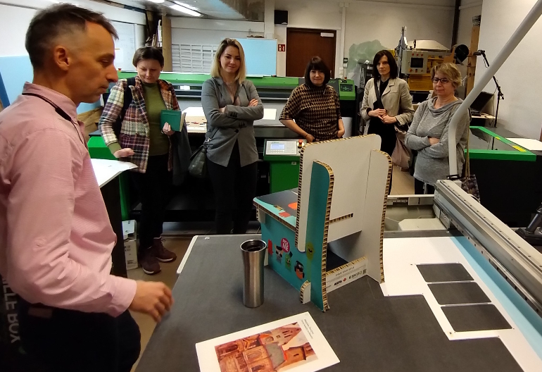 W pracowni Kulkokracja pracownik objaśnia działanie poszczególnych maszyn. Uczestnicy szkolenia obserwują z zaciekawieniem.