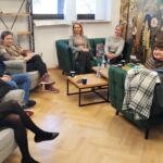 Pokój wyciszeń, na fotelach przy stoliku siedzą pracownicy UJK oraz psycholożka z KULu. Pozują, uśmiechając się do zdjęcia.