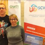 Uśmiechnięci i pozujący do zdjęcia pracownicy Centrum Wsparcia Osób z Niepełnosprawnościami w auli Wydziału Pedagogiki i Psychologii.