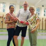 Zdjęcie uśmiechniętych pracowników UJK w Kielcach, tuż przed rozgrywką w Boccie. W tle sala sportowa Uniwersytetu Adama Mickiewicza w Poznaniu.