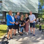 Pracownicy Centrum Wsparcia wraz z prowadzącą konferencję i trojgiem pracowników z innych uczelni stoją przed budynkiem Wydziału, w którym odbywało się wydarzenie.