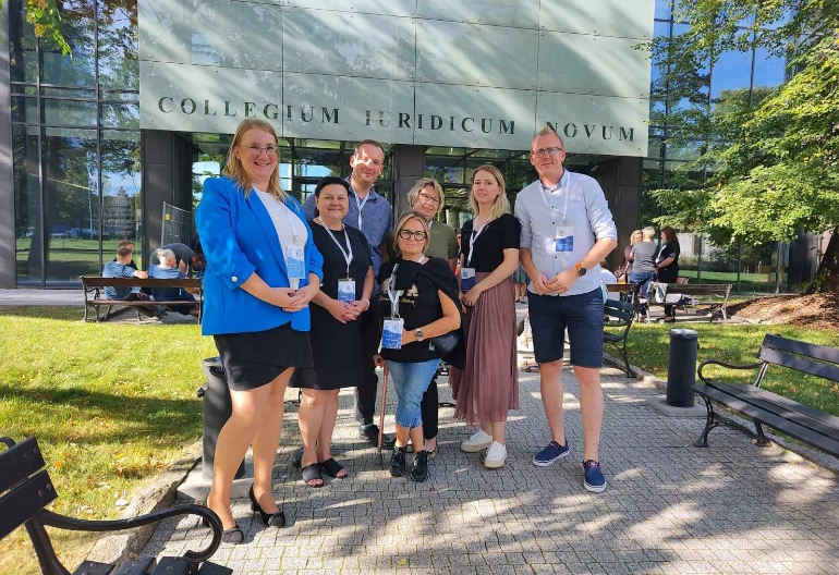 Pracownicy Centrum Wsparcia wraz z prowadzącą konferencję i trojgiem pracowników z innych uczelni stoją przed budynkiem Wydziału, w którym odbywało się wydarzenie.